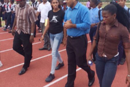  Minister of Sport, Dr. Frank Anthony and US hurdler, Kristi Castlin walking on the Synthetic Track at Leonora with some students.
