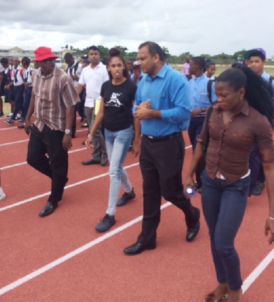  Minister of Sport, Dr. Frank Anthony and US hurdler, Kristi Castlin walking on the Synthetic Track at Leonora with some students. 