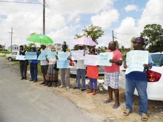 The protesters with their placards in front the Region Six RDC office on Tuesday. 