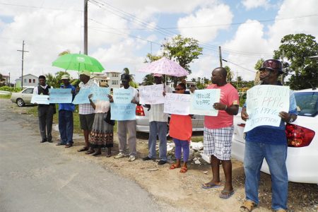 The protesters with their placards in front the Region Six RDC office on Tuesday.
