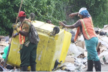 Mayor and City Council workers emptying their garbage bin at an illegal dump site located at the corners of Schumacker and Water streets. (Mark Jacobs photo)