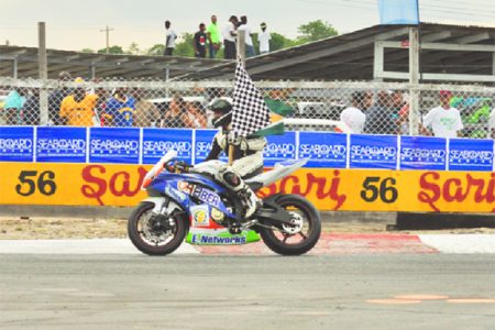 Nikhil Seeraram celebrating with the checkered flag yesterday. (Orlando Charles photo)