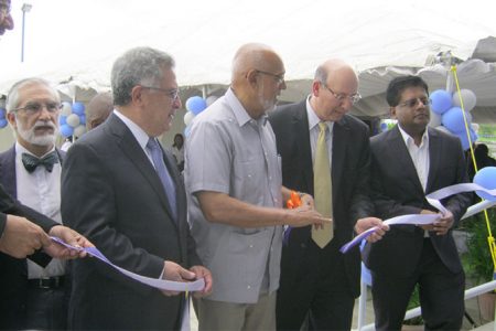 President Donald Ramotar (third from right), assisted by Vice Chairman and Executive Vice President, Unicomer Guyana Group Guillermo Siman and others, cuts the ribbon to officially open the facility.
