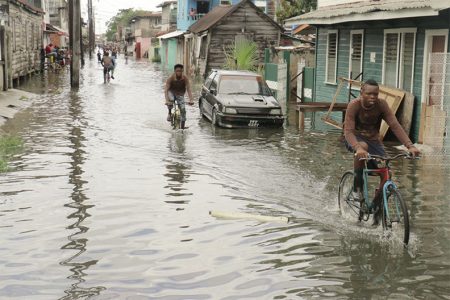 A street now covered with water: Riding through Albouystown yesterday.