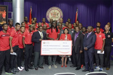 Payment time: Members of the Trinidad and Tobago Soca Warriors and the technical staff receive their cheque for $9, 64,368 from Prime Minister Kamla Persad-Bissessar at the Office of the Prime Minister, St Clair yesterday. Standing with the cheque are team captain Kenwyne Jones, centre, general secretary of the Trinidad and Tobago Football Association Sheldon Phillips, left and the Prime Minister. Next to the Prime Minister is Minister of Sport Dr Rupert Griffith.
