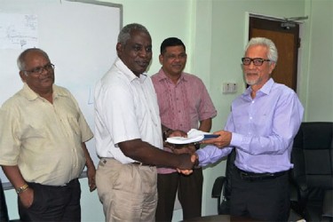 Minister of Public Works Robeson Benn presents contract documents to Managing Director of Surrey Paving Leslie Chang as BK International’s Brian Tiwarie (centre) and Permanent Secretary in the Ministry of Public Works Balraj Balram (left) look on. (GINA photo) 