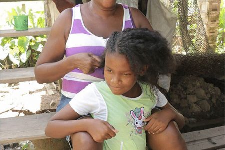 Verna Sam sits on her
step combing her
daughter’s hair.
Photo by Arian Browne
