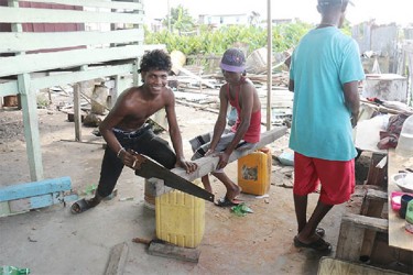 These young men are cutting wood to build a house  