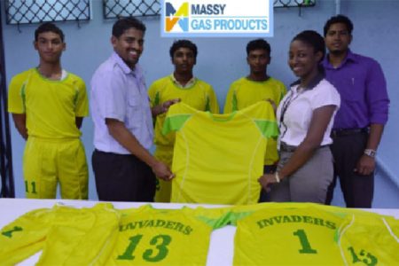 Invaders Captain Vaickesh Dhaniram receives the uniforms from Massy Gas Products Customer Services Officer Elicia Chapman while some members of the team look on.

