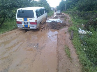 Vehicles had difficulty in navigating the large, muddy potholes along the road