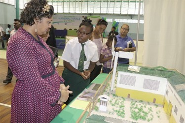 A student of the Richard Ishmael Secondary School explaining her school’s project, titled “Making a Multi-Solar Energy Saving Device” to Minister of Education Priya Manickchand at the opening day of the finals of the Sagicor Visionaries Challenge at the Cliff Anderson Sports Hall. The project was conceived due to the regular power outages faced by the school.  (Arian Browne photo) 