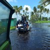 Media personnel hitch a ride on the tray of a police vehicle as they survey the damage done to the Manzanilla-Mayaro Road yesterday following floods at the weekend.
