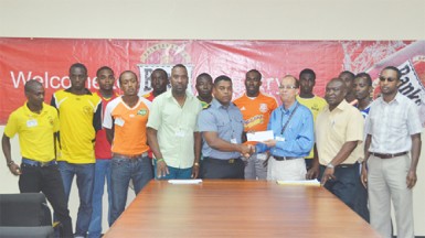 GFA President Vernon Burnette (third from left in front row) accepting the sponsorship cheque from Banks Beer Brand Manager Brian Choo-Hen during the launch of the Banks Beer Cup while members of Banks DIH, GFA and the competing teams look on.  