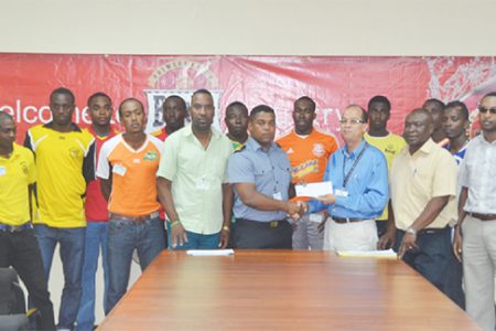 GFA President Vernon Burnette (third from left in front row) accepting the sponsorship cheque from Banks Beer Brand Manager Brian Choo-Hen during the launch of the Banks Beer Cup while members of Banks DIH, GFA and the competing teams look on.
