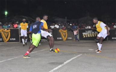West Front Road’s Colin Nelson (centre) in the process of completing a pass to teammate Hubert Pedro (right) while being challenged by an island All-Stars player (no.32). 