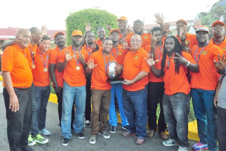 The jubilant national rugby squad and now seven-time NACRA champions pose with the coveted trophy shortly after arriving at the Cheddi Jagan International Airport, Timehri yesterday. (Orlando Charles photo)
