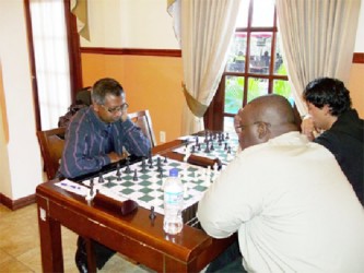 Veteran chess player Loris Nathoo contemplates his next move against Guyanese Olympian Ronuel Greenidge in the Umada Cup chess tournament at the Sleep Inn hotel. Playing the black pieces,  Nathoo won a pawn during the game, but with Bishops of opposite colours, the inevitability of a draw was assured for Greenidge. Nathoo began the tournament with a one game disadvantage because he failed to appear for his first game. He rebounded, however, to claim the Under-1700 prize, a trophy, and the small matter of US$500 for his efforts. 