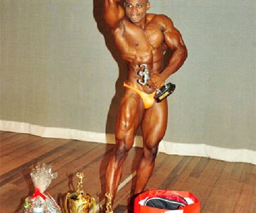 Mr. Flex Night 2014, Godfrey Stoby flexes with his spoils after posing his way to the overall honours. (Orlando Charles photo)

