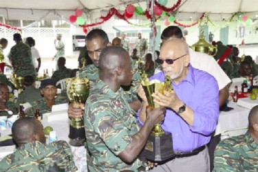 President Donald Ramotar (right) being offered a sip from the “Trophy” by a rank of the Guyana Defence Force (GINA photo) 