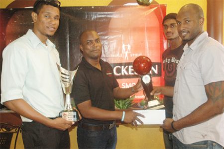 Ryan Gullen (right) of the victorious Pitbulls unit collecting the championship trophy and winner’s cheque from Mackeson Brand Manager Jamal Douglas while teammates Jermin Slater (left) and Akeem Kanhai look on.