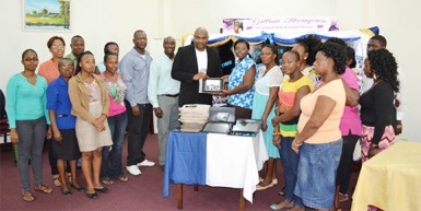 Chief Executive Officer of Southern Systems Karl Moore (tenth, left) hands over the donation in the presence of library staff and Thompson’s family.