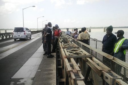 Police officers and Demerara Harbour Bridge Corporation officials standing at the spot where the unidentified woman jumped to her death yesterday, off the Demerara Harbour Bridge.
