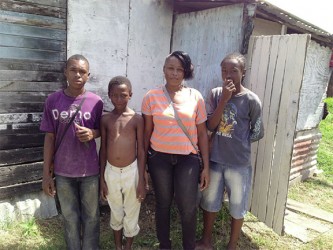 Corina with her sons and brother (at left) in front of her humble ‘apartment’ 