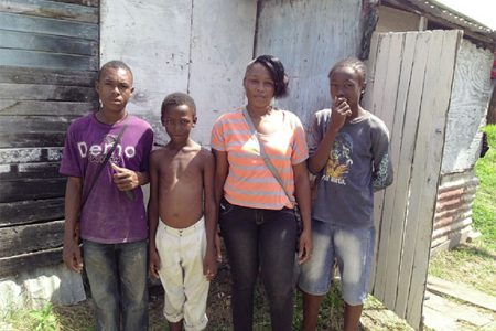 Corina with her sons and brother (at left) in front of her humble ‘apartment’
