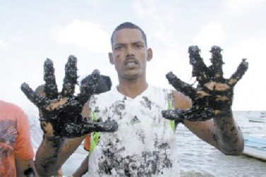 Fisherman Vishnu Cyril shows his oil-stained hands at Otaheite Fishing Depot, Oropouche, on Thursday. (Trinidad Guardian photo)