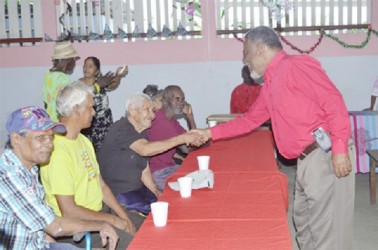 Prime Minister Samuel Hinds greets a resident of the Dharm Shala at the luncheon (GINA photo) 