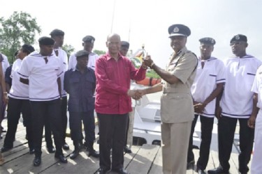 Minister of Home Affairs, Clement Rohee (left)  handing over the keys to the vessels to Police Commissioner, Seelall Persaud as ranks of the Guyana Police Force Marine Department look on (GINA photo) 