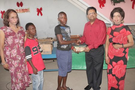 Finance Minister Dr Ashni Singh presenting a gift at today’s Dharm Shala party for children in Albouystown. At left and right respectively are Pamela and Kella Ramsaroop, daughters of the late Harry Ramsaroop who ran the home for the indigent for many years.