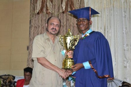      Minister of Health Dr. Bheri Ramsaran presenting a trophy to the best graduating student, Lester Christian (GINA photo)