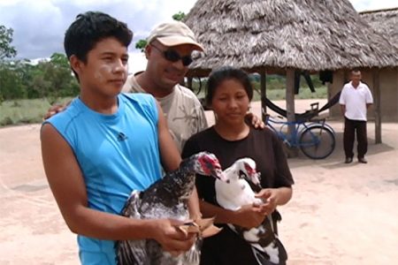 A  safarian takes a photo with two young Rupununi residents and their ducks (GINA photo)