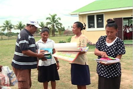Frank Singh of Rainforest Tours presents educational materials to teachers in the South Rupununi (GINA photo)