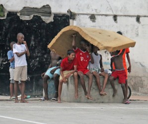 These youths sheltered under an old mattress today as they watched a street football game along Independence Boulevard.