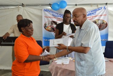 A typist-clerk (left) receives her token from Minister of Local Government, Norman Whittaker (GINA photo) 