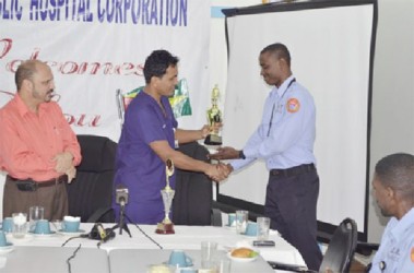 Georgetown Public Hospital Corporation’s Director of Accident and Emergency Department, Dr. Zulfikar Bux (second from left) handing over the trophy for best performing Emergency Medical Technician in 2014 to Ron Morris as Minister of Health Dr. Bheri Ramsaran looks on. (GINA photo)