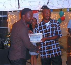 Dexter Nolan, right, of the National Cricket Centre in Balmain, Couva, receives a certificate of participation from Foi George of the National Gas Company at a recent function at the Sir Frank Worrell Development Centre. Photo courtesy T&T Cricket Board
