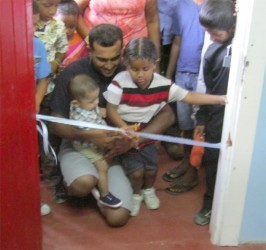 A student of the St Lawrence Nursery School assisting in cutting the ribbon. 