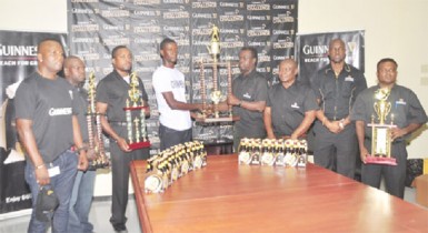 Joint tournament coordinator Travis Best (fourth from left) receives the championship trophy from Banks DIH representative Ezequiel Beard while other members of the company look on. 