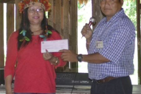 Minister of Amerindian Affairs Pauline Sukhai presents a $10M cheque to Masakenari’s Toshao Paul Chekema for the development of the trail leading to the village. (Government Information Agency photo)