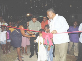 Young residents of the area assist PM Sam Hinds with ribbon-cutting duties