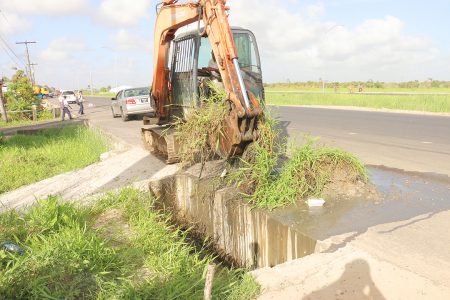 Clearing thick weeds which were growing in the recently constructed concrete drains at Prospect along the East Bank Demerara Public Road.