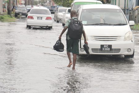 This schoolboy had to navigate the flooded Quamina Street today with shoes in hand.