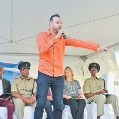 Chutney soca artiste Ravi B performs for patrons on the Brian Lara Promenade yesterday during the launch of the “Wrong Mix: Alcohol and Lyrics” road safety public awareness campaign. Looking on, second from left, is acting Police Commissioner Stephen Williams