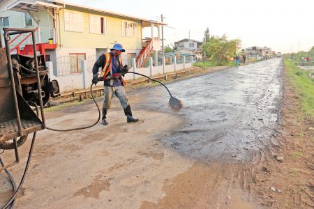 Workers on Tuesday laying down the first layer of tar along the Section B Sophia Entrance Road which is under rehabilitation.
