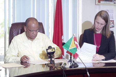 Home Affairs Minister Clement Rohee and Canadian High Commissioner to Guyana Dr Nicole Giles signing the Memorandum of Understanding.