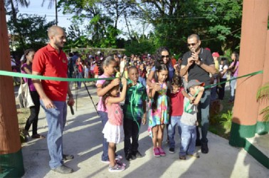 Damian Fernandes (left), Commissioner of the Protected Areas Commission and Minister of Natural Resources and the Environment Robert Persaud (right) observe the cutting of the ribbon at the commissioning of the Zoological Park’s Petting Zoo yesterday. (See page 10) 