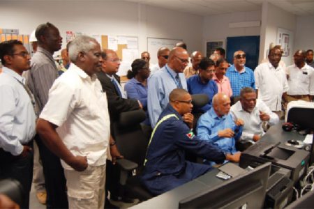 A young technician (seated, left) shows how the system works while President Donald Ramotar (seated, centre and Prime Minister Sam Hinds (right) look on. They are flanked by government and GPL officials.